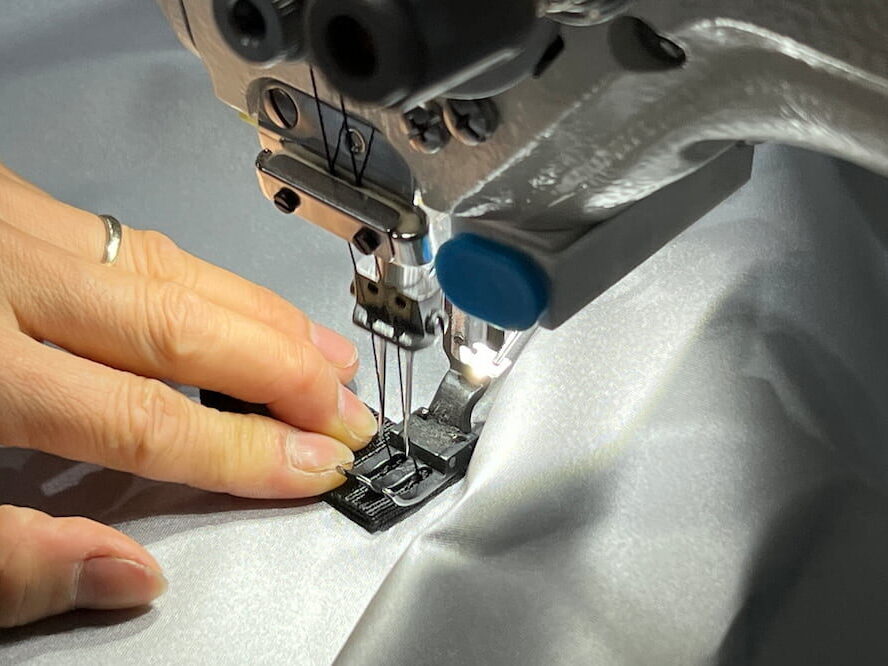 A factory worker skillfully sewing fabric using an industrial sewing machine